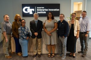 Two EDA representatives and six members of EI2's leadership group standing in front of a wall