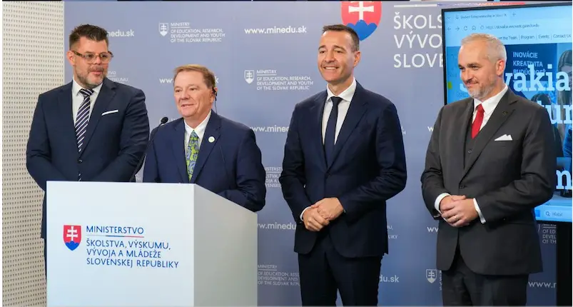 Four men standing up on a dais